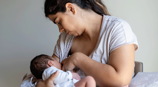 mother breastfeeding newborn baby at home