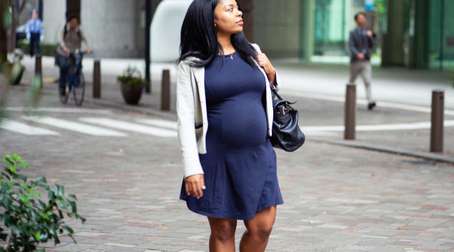 sad pregnant woman walking through a city
