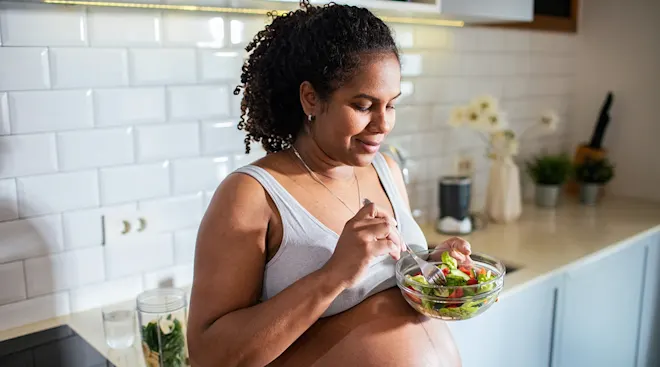 pregnant woman eating a salad at home