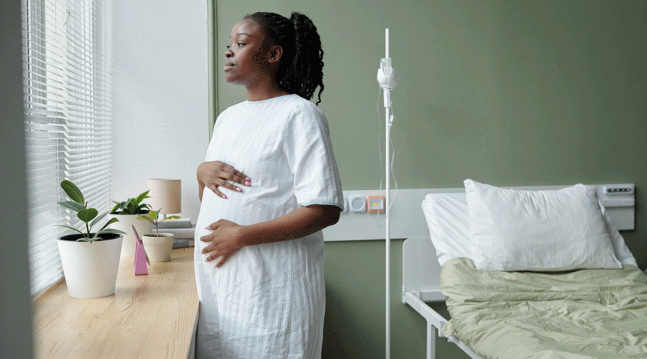 black pregnant woman looking out of hospital window