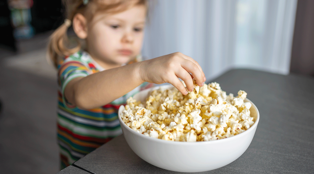 toddler reaching for a bowl of popcorn