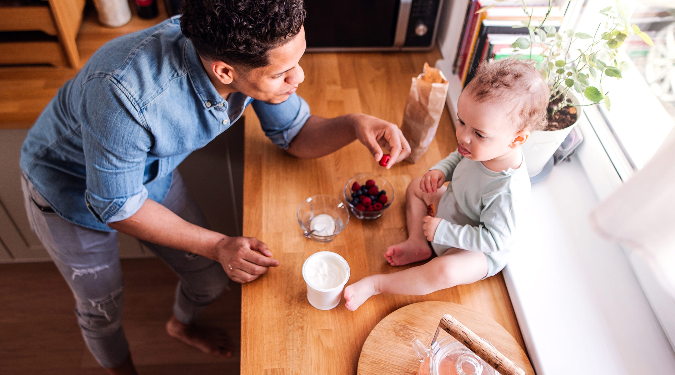 dad eating healthy food with his toddler in the kitchen