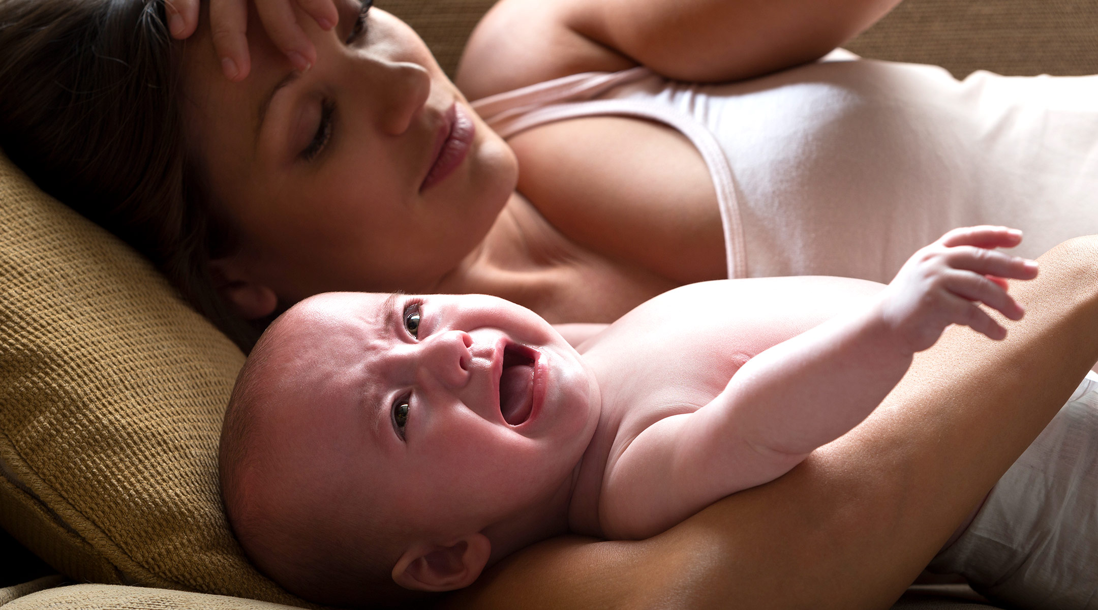 mom holding baby on couch crying 