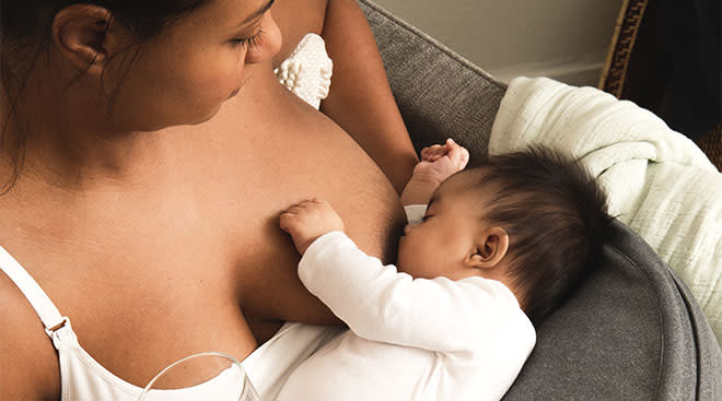 Frida's new nursing pillow in use, mom breastfeeding her baby. 