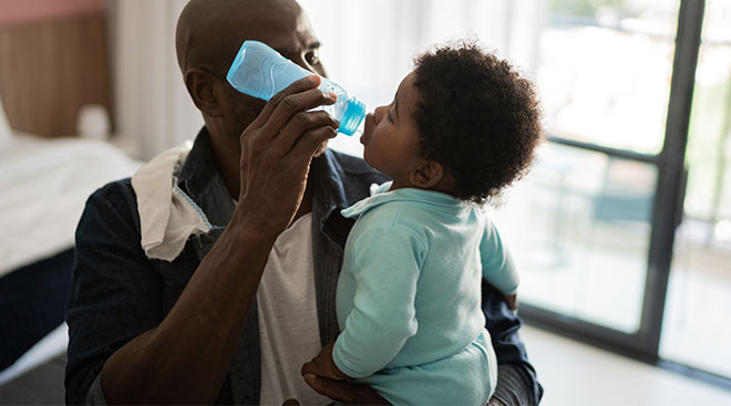 Toddler drinking water from a bottle. 