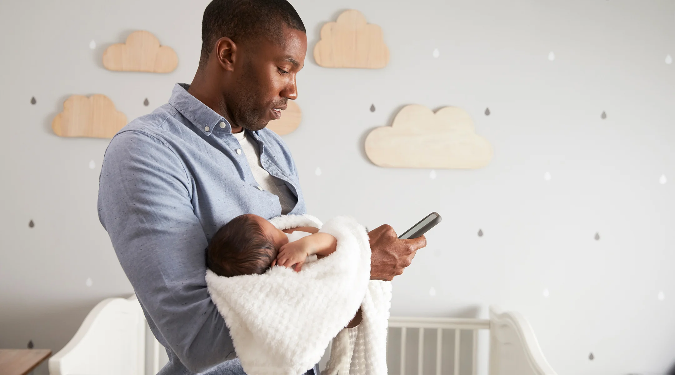 dad on phone while holding newborn