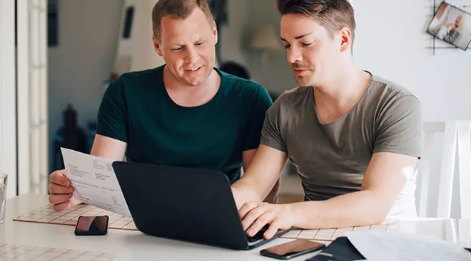 Same sex couple looks at laptop computer together