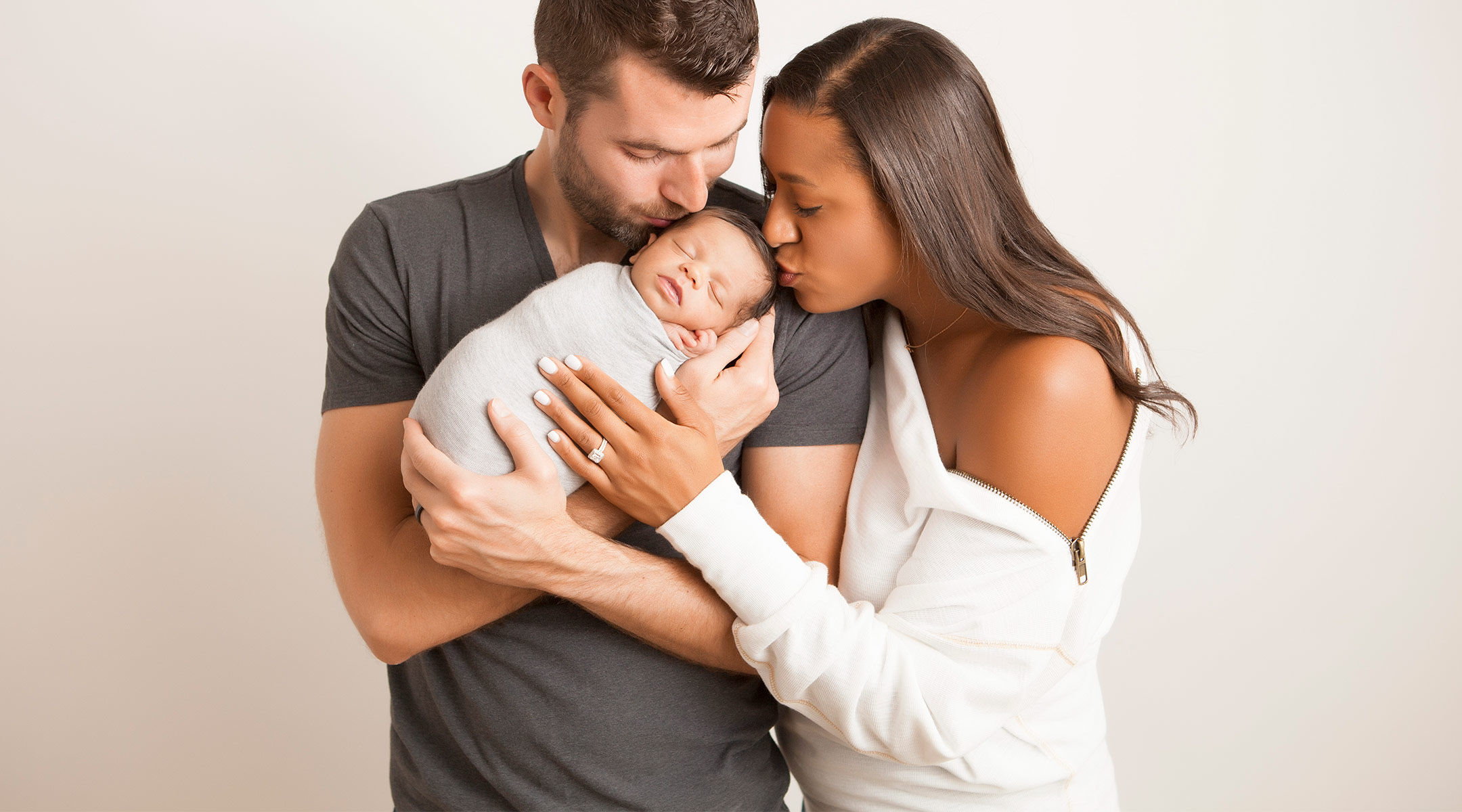 writer posing with her newborn and husband
