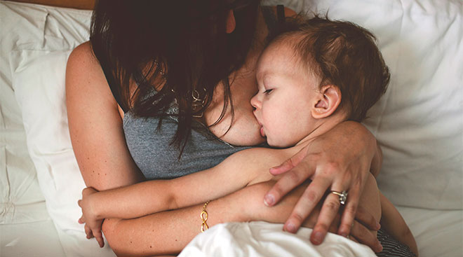 mom sitting in bed breastfeeding her baby