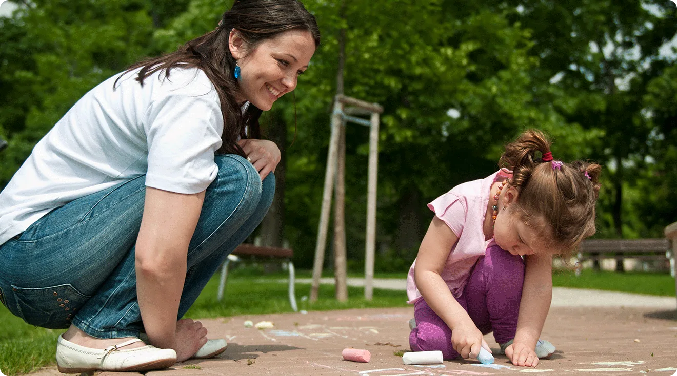 mom watching toddler play with chalk outside