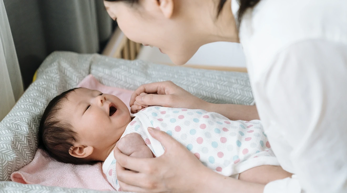 mother smiling at baby on changing table