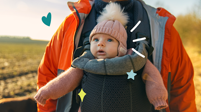 baby in forward-facing carrier on parent's chest outdoors on a walk