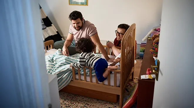 two fathers sitting in bedroom with toddler