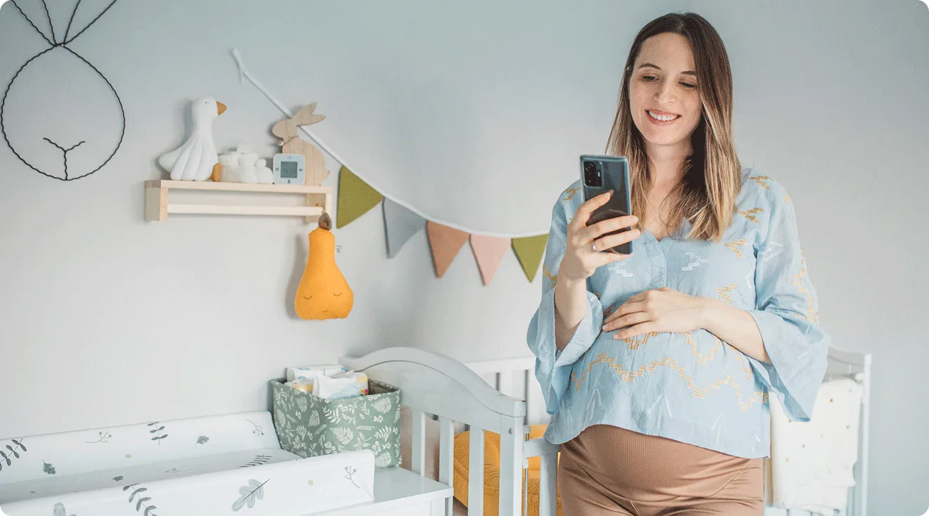 pregnant mom looking at phone in baby nursery at home