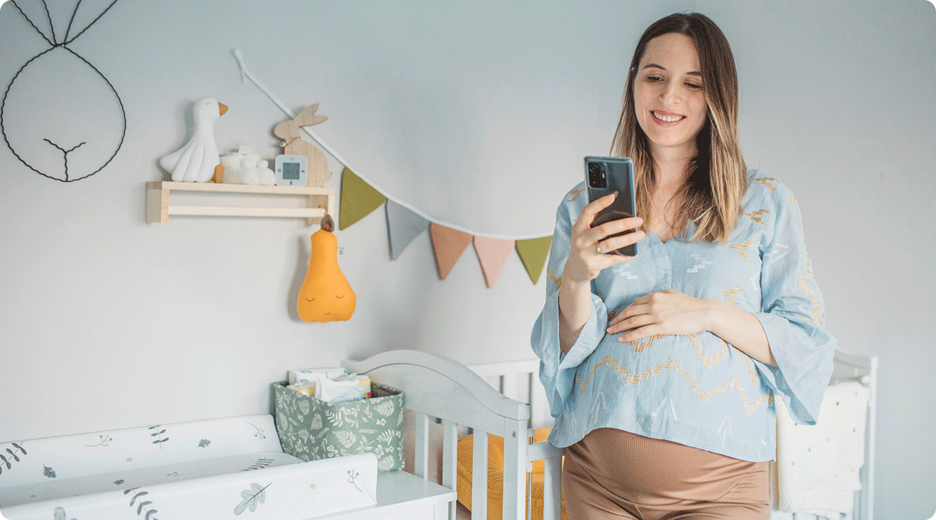 pregnant mom looking at phone in baby nursery at home