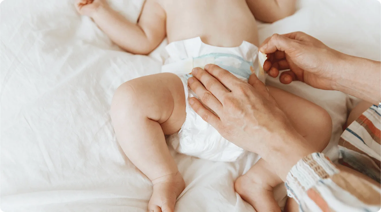 mom securing diaper on baby