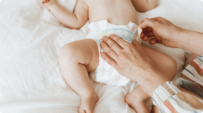 mom securing diaper on baby