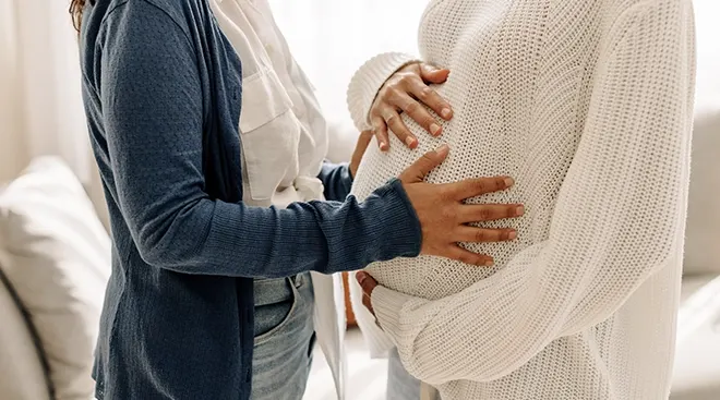 close up of LGBTQ couple touching pregnant belly