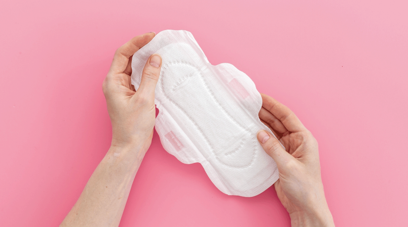 hands holding a menstrual pad on pink background