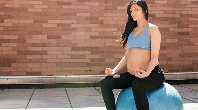 pregnant woman sitting on exercise ball