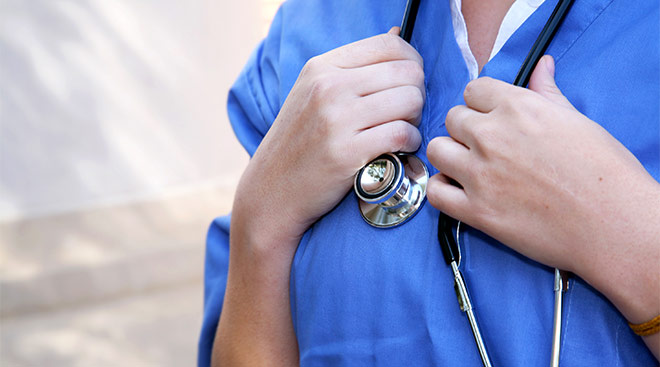 close-up of nurse clutching her stethoscope with her hands