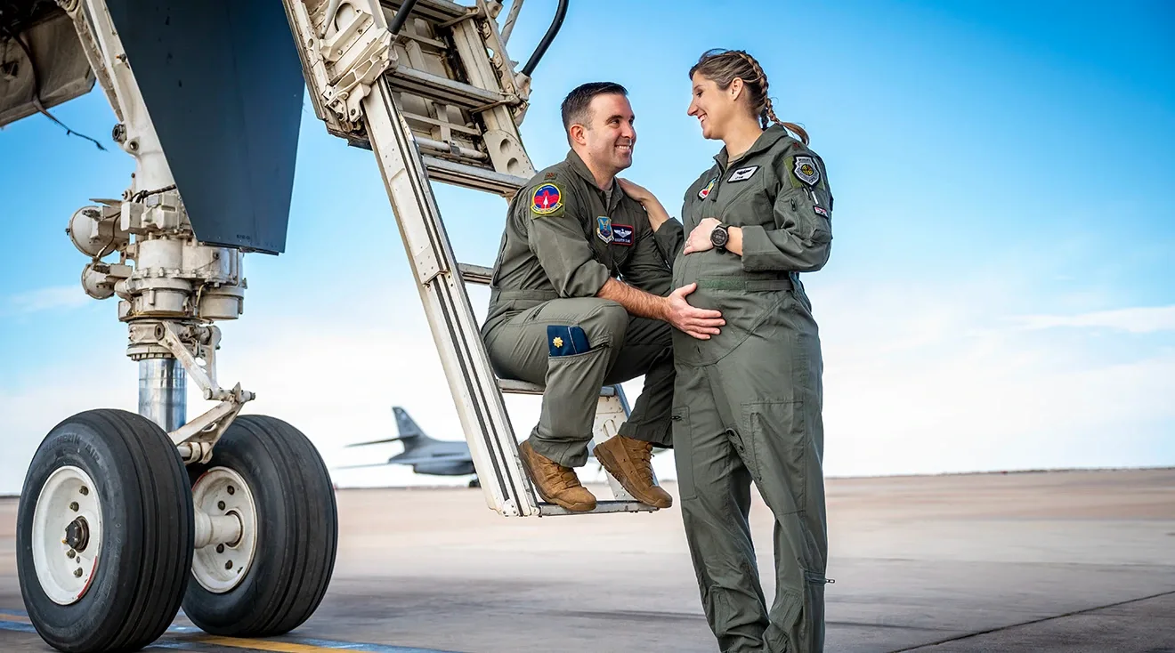 pregnant Maj. Lauren Olme her husband, Maj. Mark Olme standing near airplane