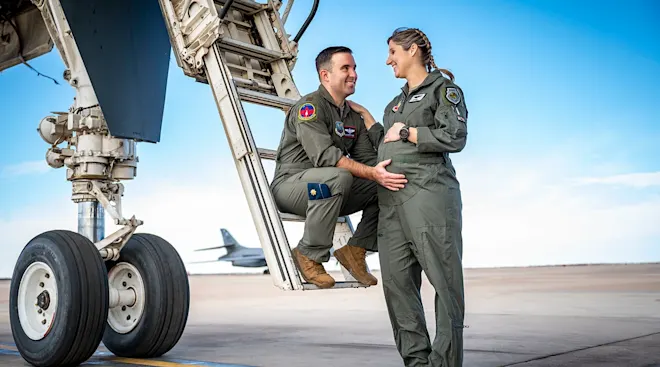 pregnant Maj. Lauren Olme her husband, Maj. Mark Olme standing near airplane
