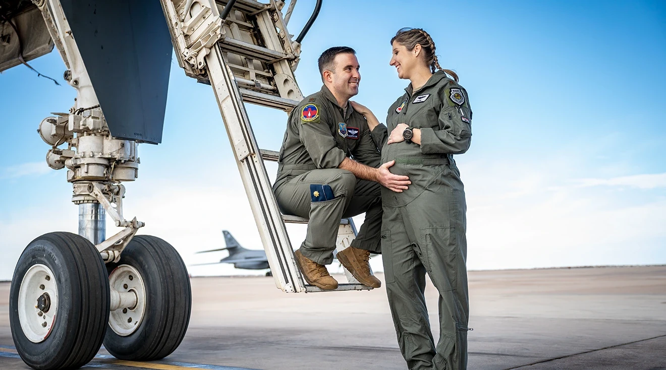 pregnant Maj. Lauren Olme her husband, Maj. Mark Olme standing near airplane