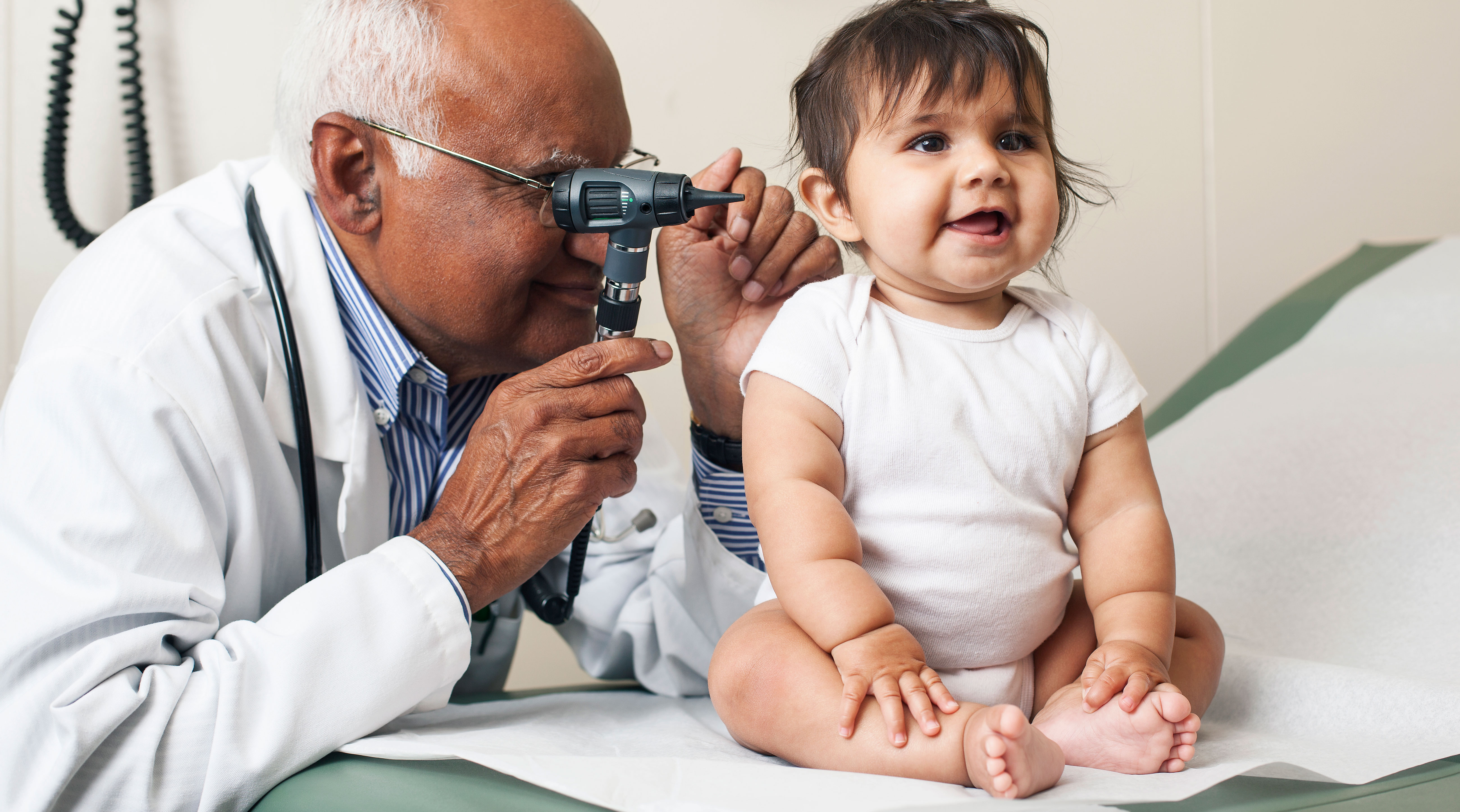 pediatrician checks baby's ear during well visit