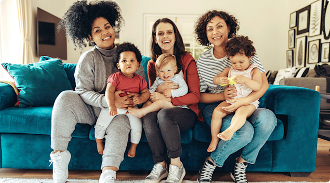 group of smiling moms sitting on couch with their babies