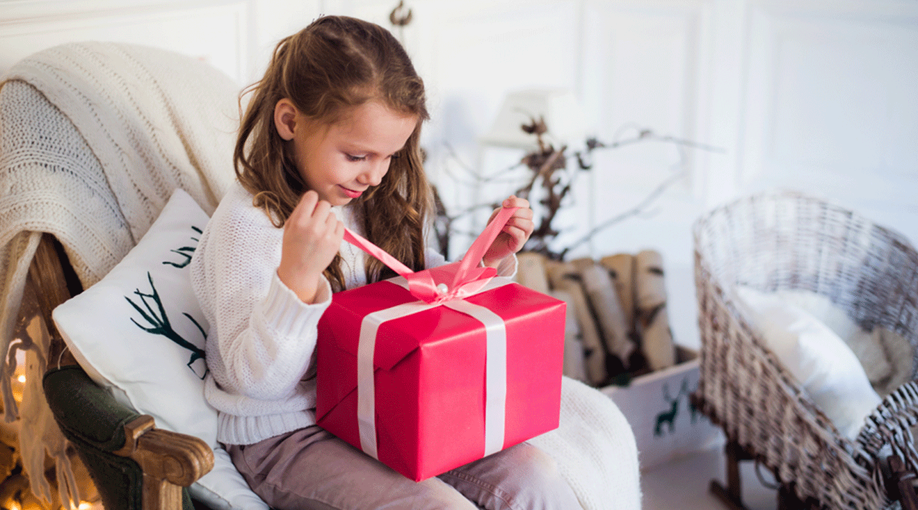 little girl opening holiday gift at home