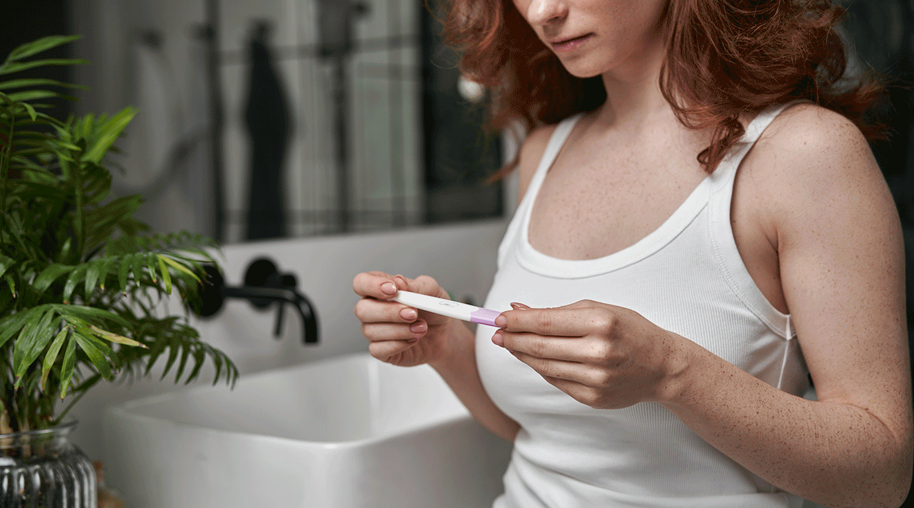 young woman looking at pregnancy test in bathroom