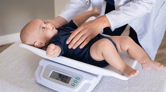 doctor weighing baby on scale