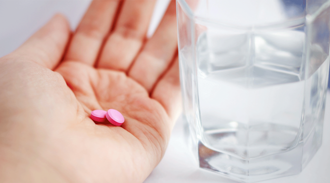 pink allergy pills in woman's hand