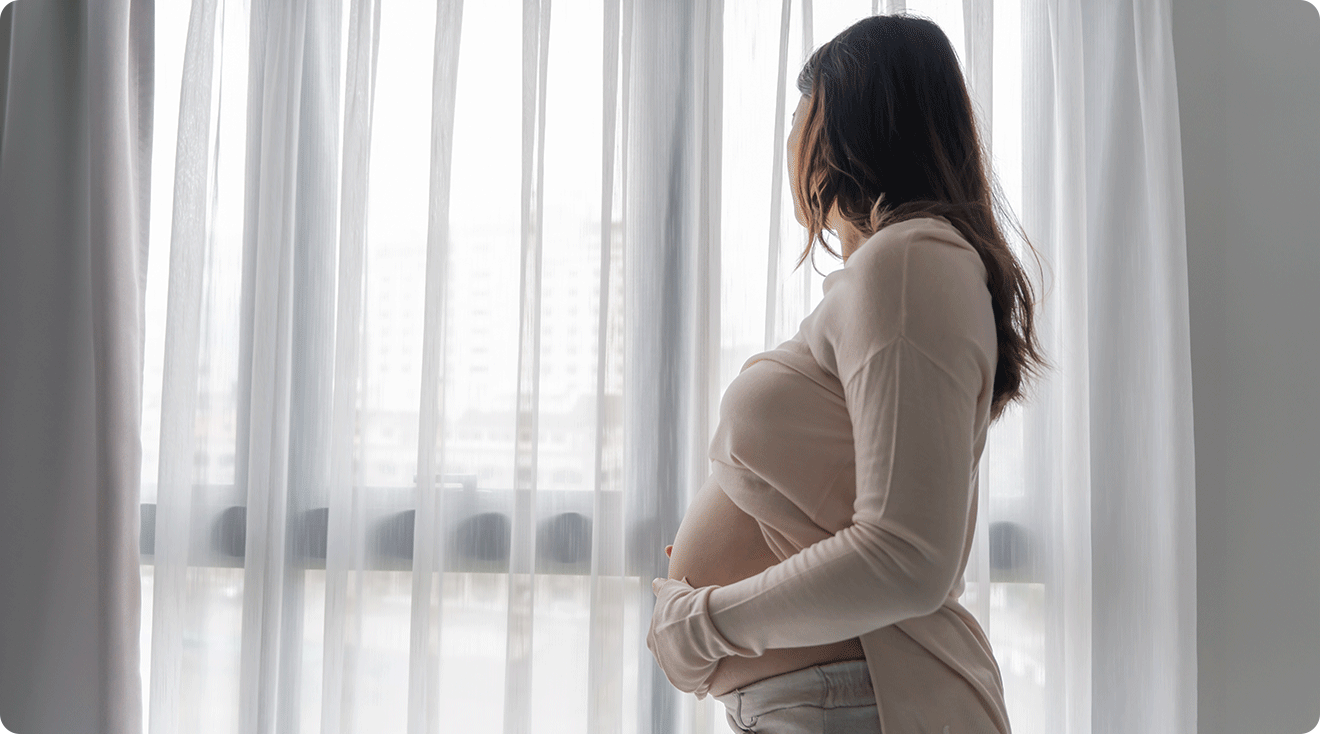 worried pregnant woman looking out window