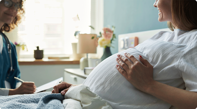 A pregnant woman talking to her healthcare provider while sitting in a hospital bed.