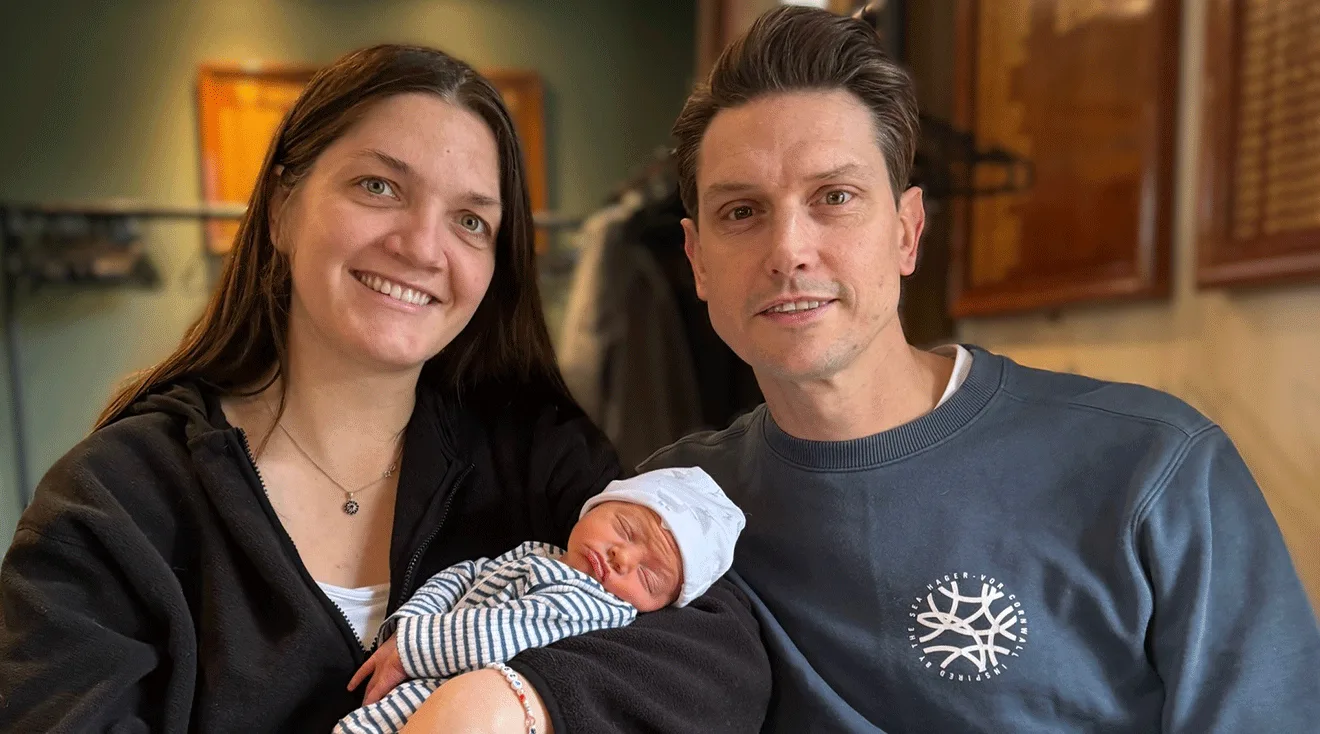 lucy and adam isaac holding their newborn baby