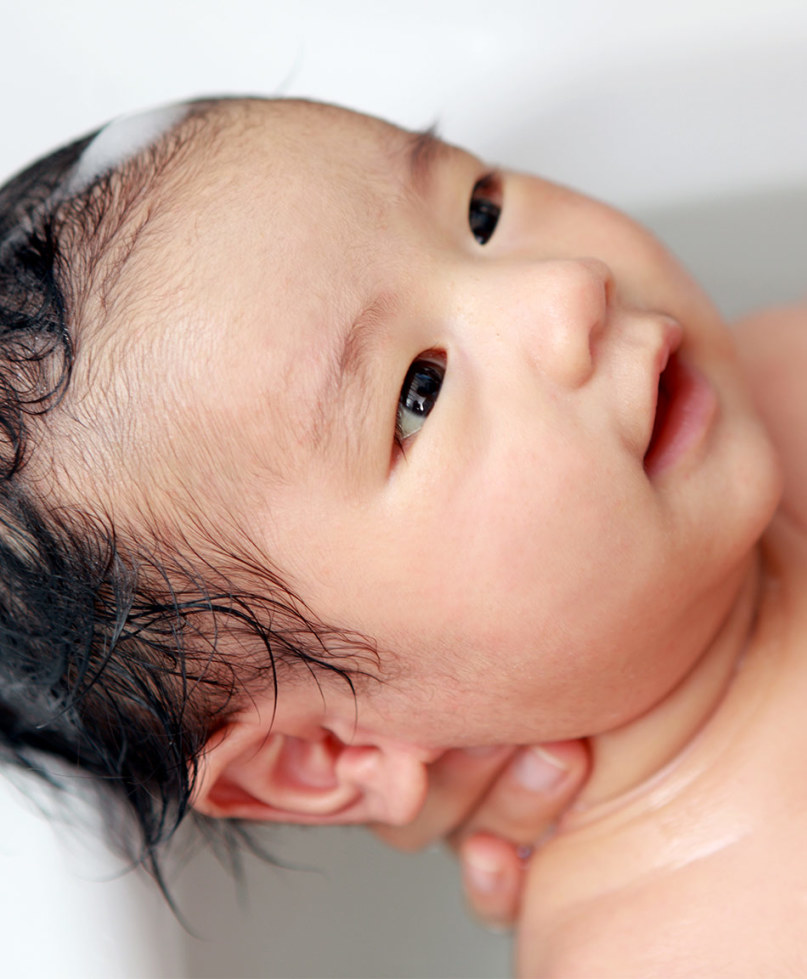 Portrait of smiling baby boy playing with thermostat of heater Stock Photo