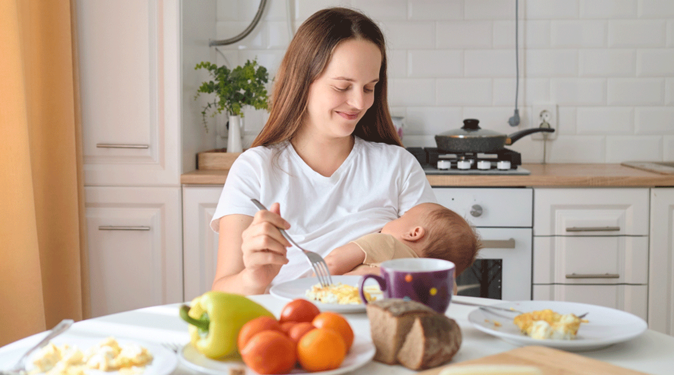 mom eating while breastfeeding baby in kitchen at home