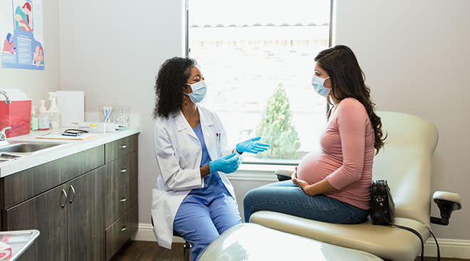 pregnant woman talking to doctor in exam room at doctor's office