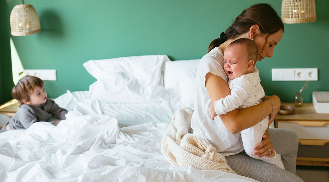 frustrated stay at home mom holds her crying baby