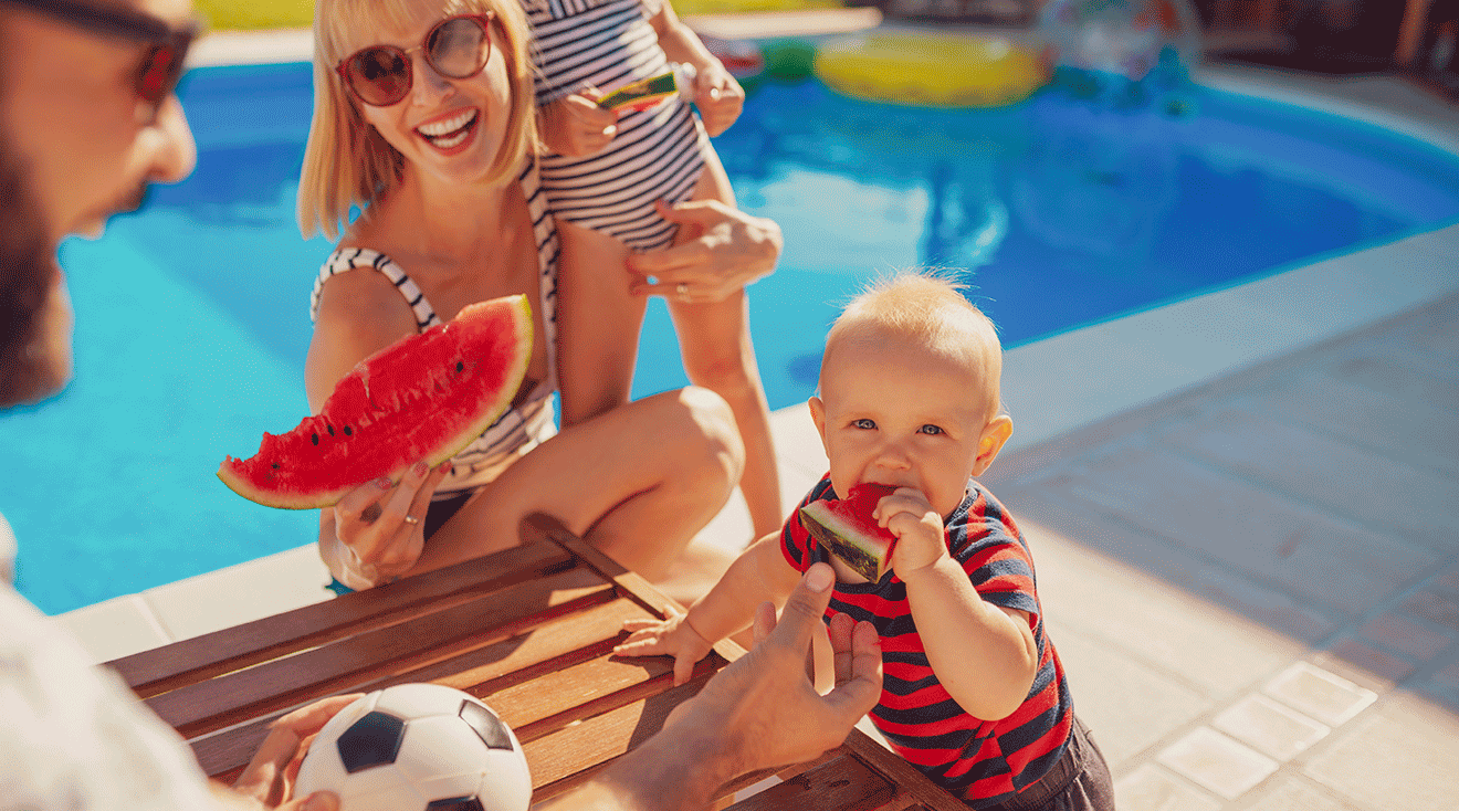 family enjoying watermelon in backyard during summer