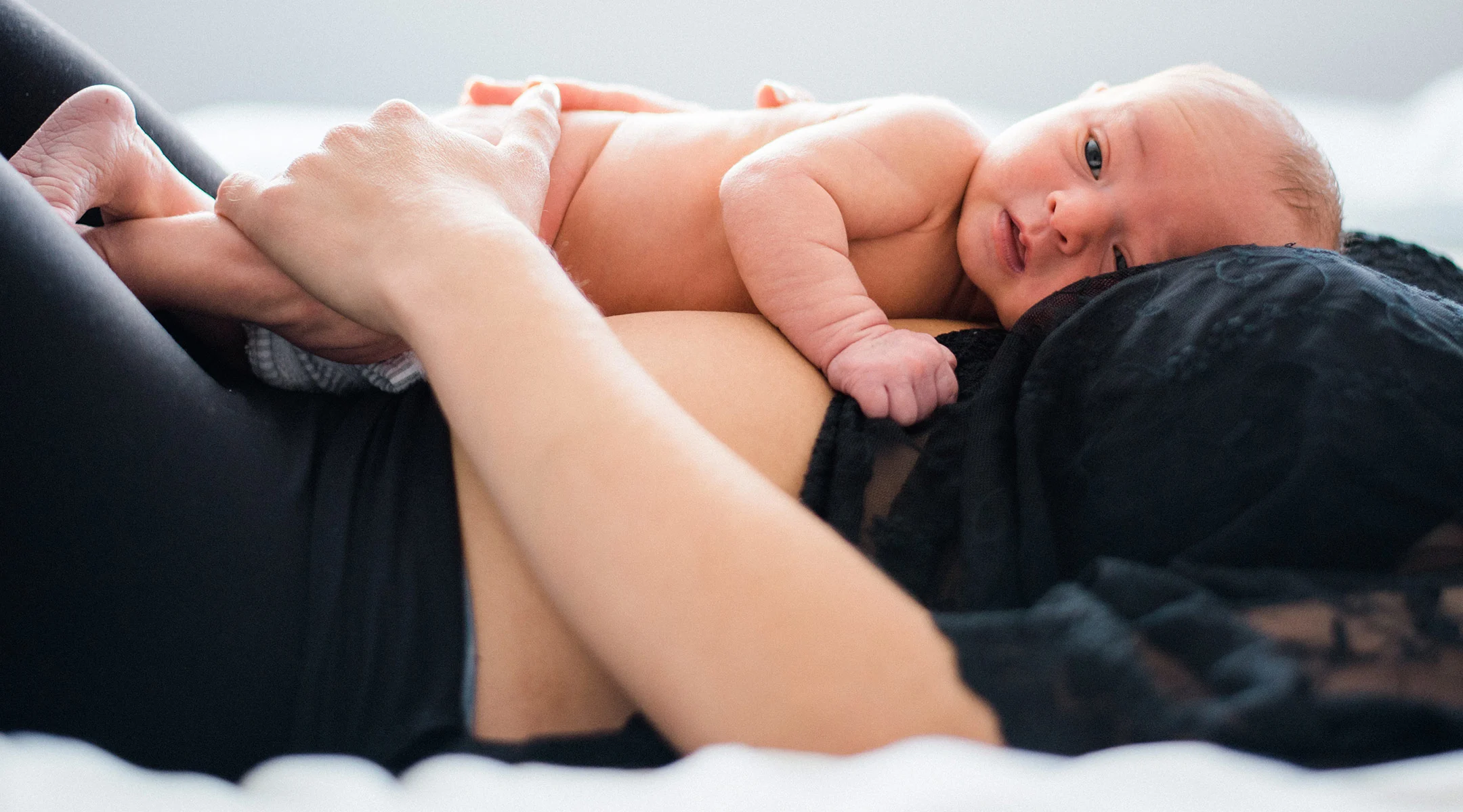 mother stroking baby who is laying on top of her