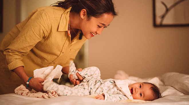 smiling mother getting her baby ready for bed