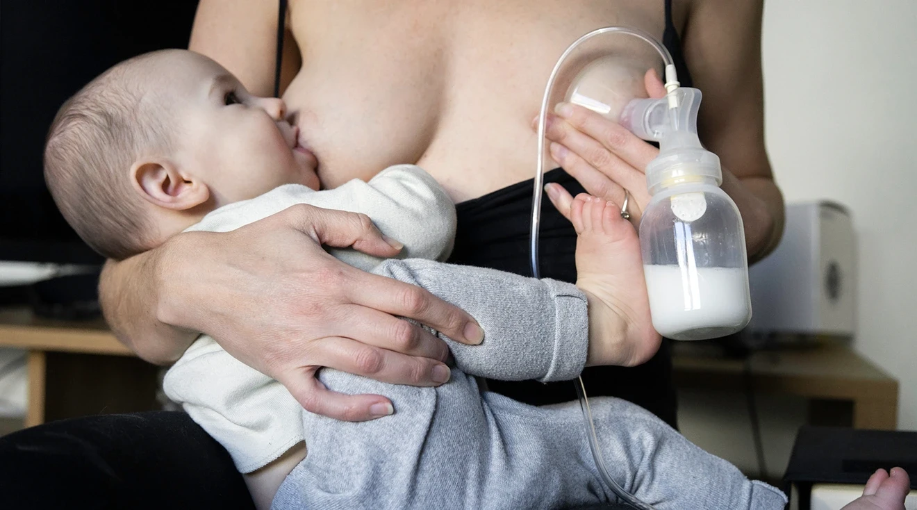 mother breastfeeding baby while pumping at the same time