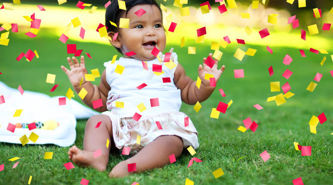 happy baby with arms up and confetti falling
