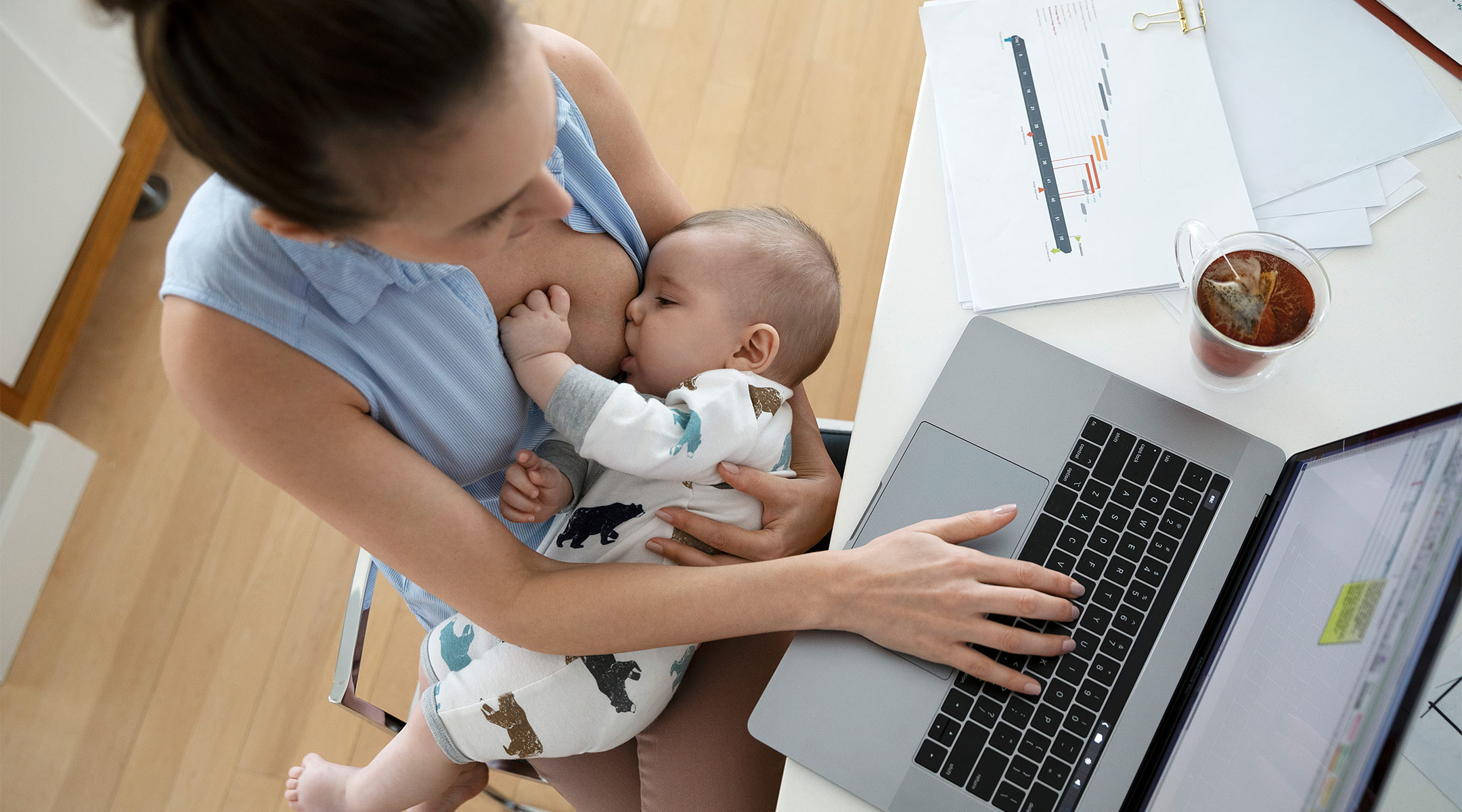 mom breastfeeding her baby while working on computer