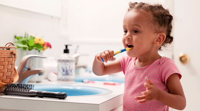 toddler brushing teeth in bathroom at home