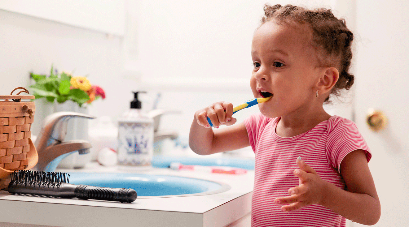 toddler brushing teeth in bathroom at home