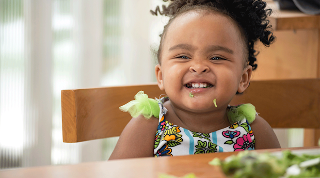 smiling little girl eating veggies